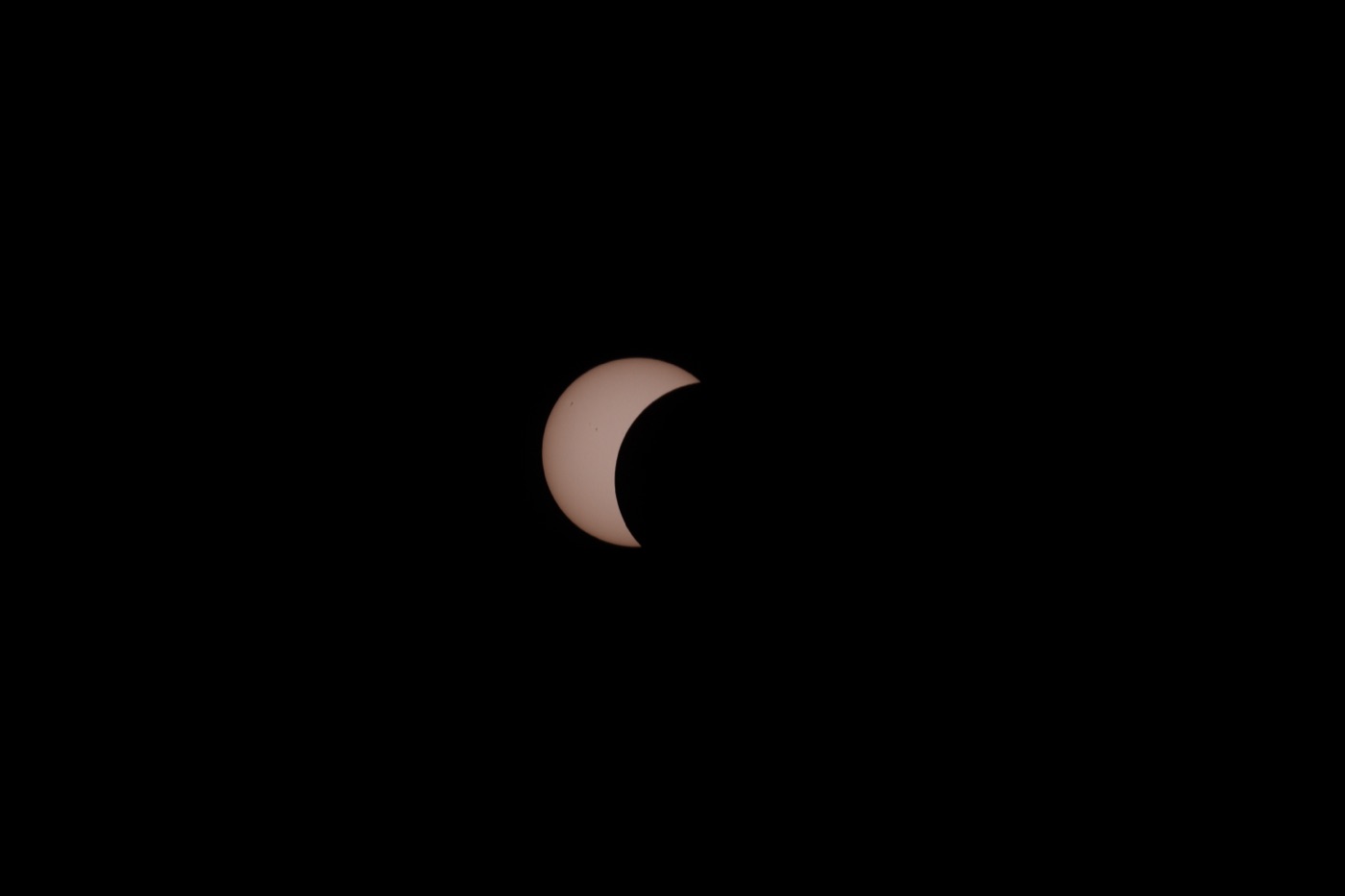 Partielle Phase: der Mond hat ein großes Stück der Sonnenscheibe abgedeckt, auf der hellen Sichel sind Sonnenflecken erkennbar